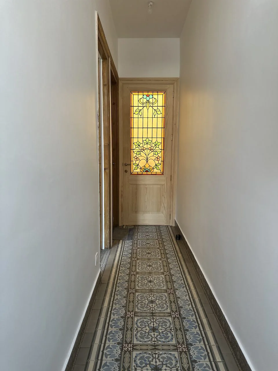 Rénovation clé en main d'une maison de 1908 à La Madeleine - après, le couloir d'entrée, ses carreaux de ciment et sa porte à vitrail